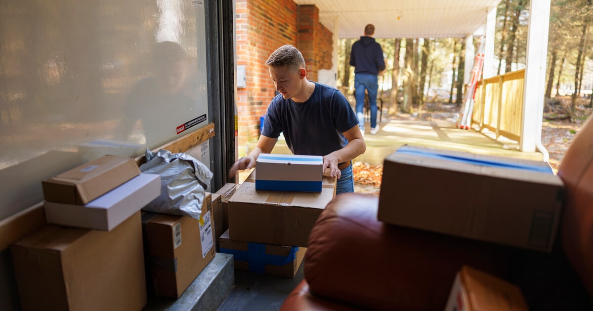 Man unloading boxes from truck is confident that he found the cheapest way to move across country.